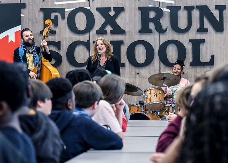 Musicians performing for students in a school cafeteria