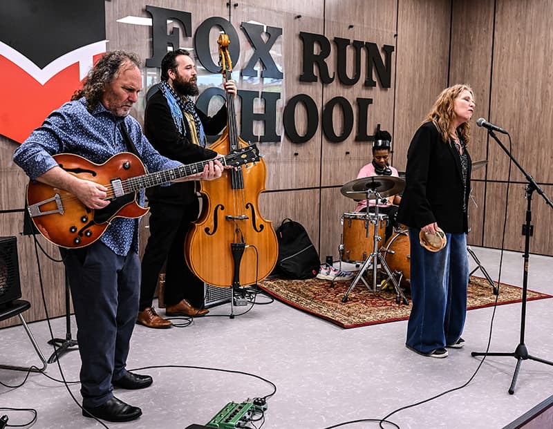 A band performing in front of a Fox Run School sign