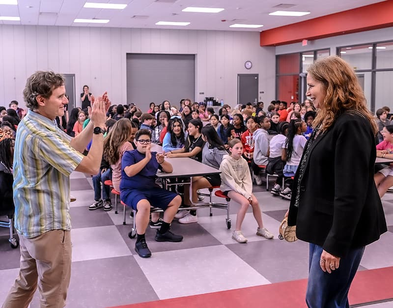 A musician high-fiving a student in a school cafeteria