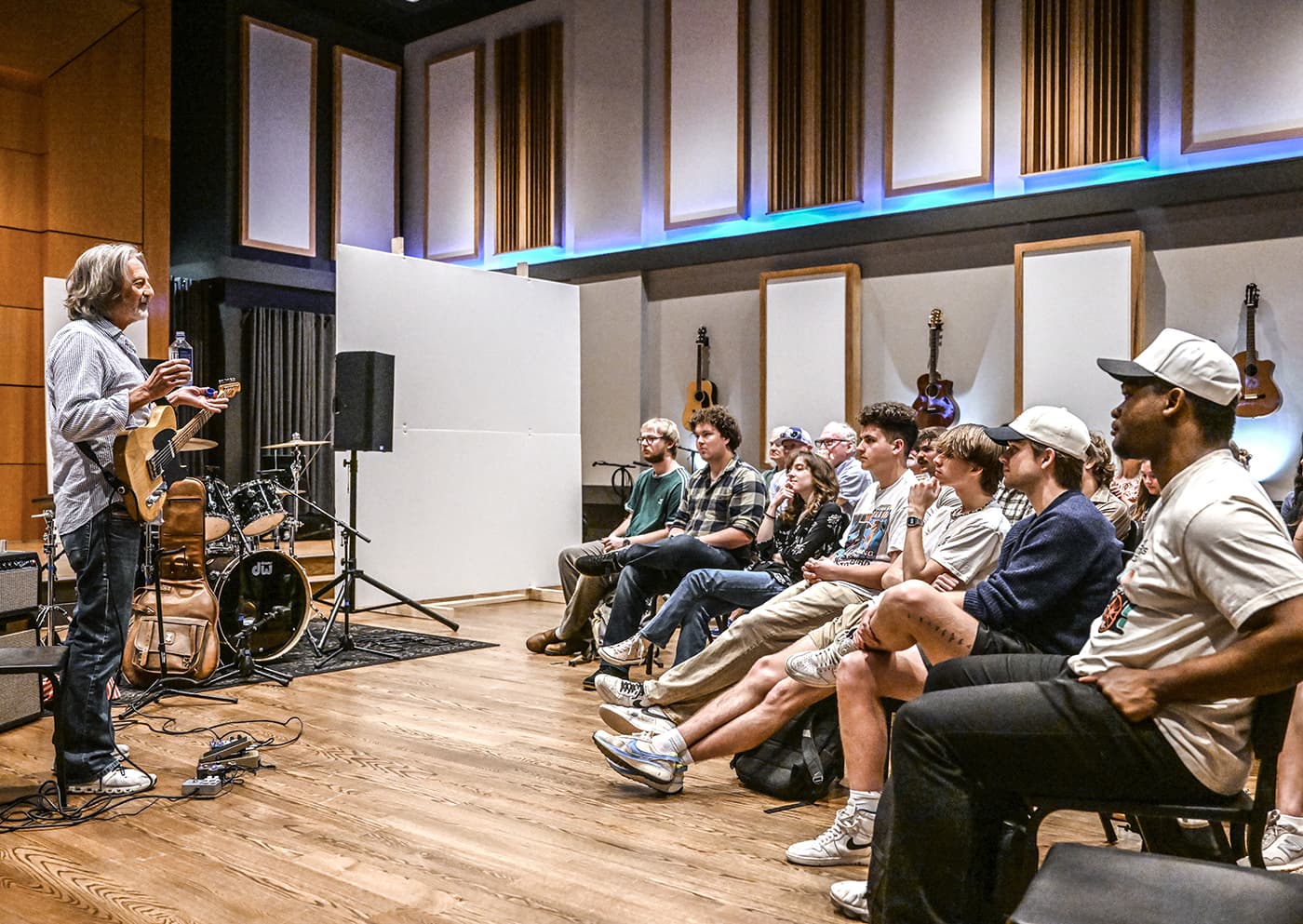 A guitarist teaching a masterclass to a seated audience